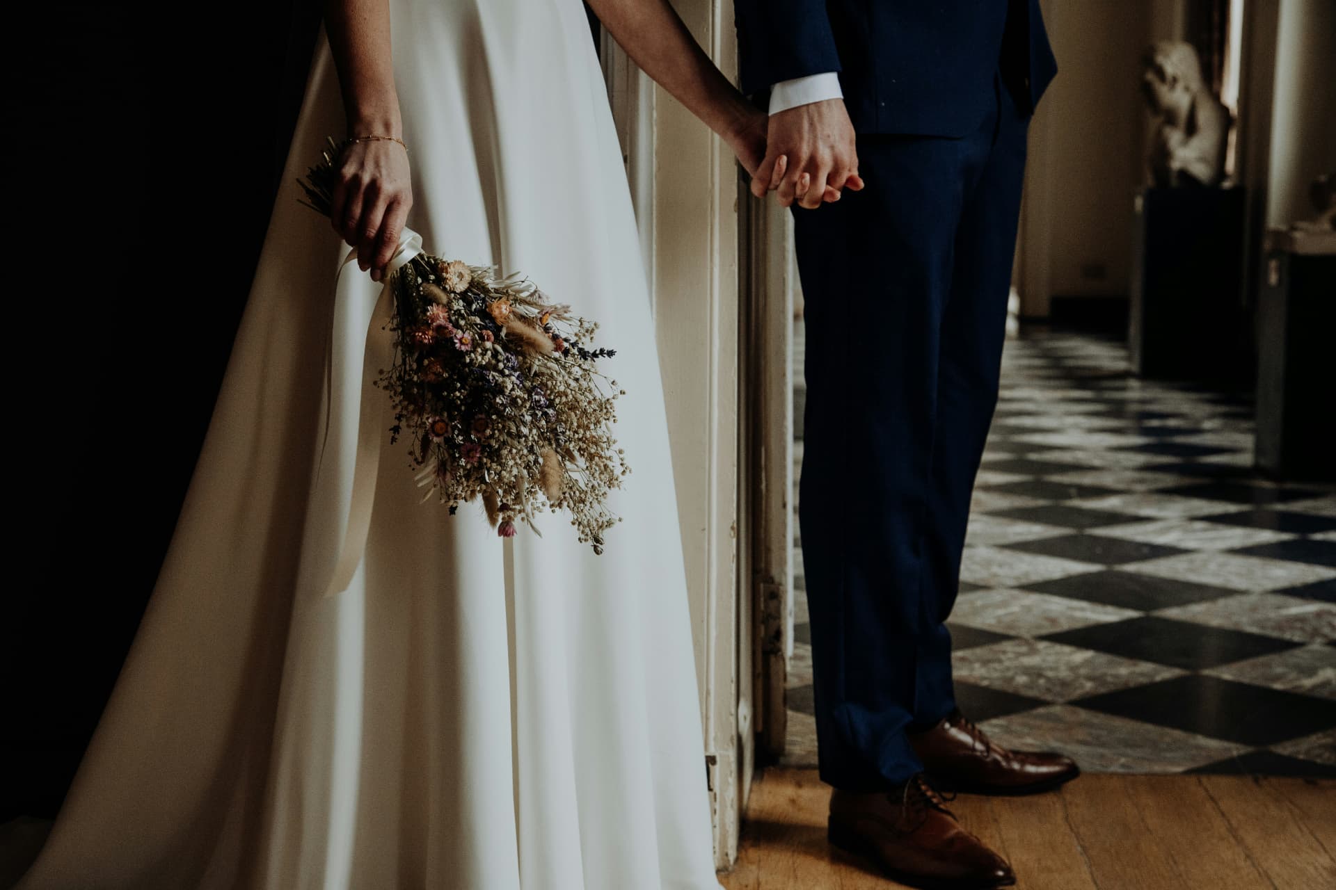 Bride and groom holding hands with dried flower bouquet